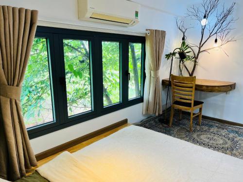 a bedroom with a bed and a desk and windows at TỊNH Retreat Phu Quoc in Phu Quoc