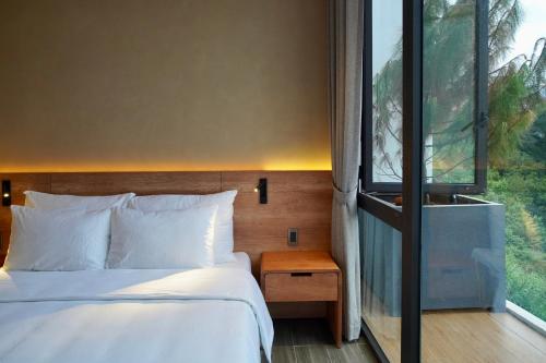 a bedroom with a bed and a large window at Là Yên Villa - Đà Lạt in Ấp Ða Lợi