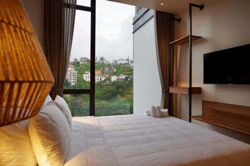 a hotel room with a bed with a large window at Là Yên Villa - Đà Lạt in Ấp Ða Lợi