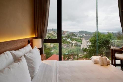 a bedroom with a white bed and a large window at Là Yên Villa - Đà Lạt in Ấp Ða Lợi