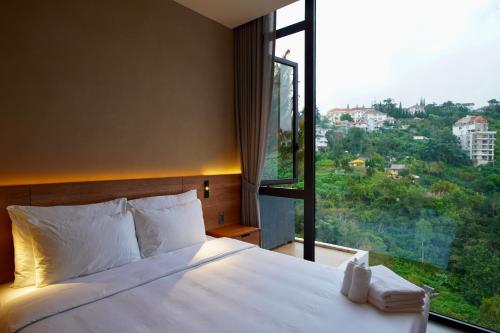 a bedroom with a white bed and a large window at Là Yên Villa - Đà Lạt in Ấp Ða Lợi
