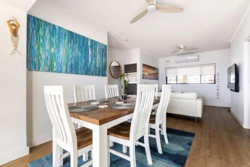 a dining room with a table and white chairs at Beach Stayz Semaphore Three Bedroom Apartment in Port Adelaide