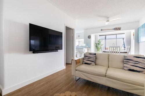 a living room with a couch and a flat screen tv at Beach Stayz Semaphore Three Bedroom Apartment in Port Adelaide