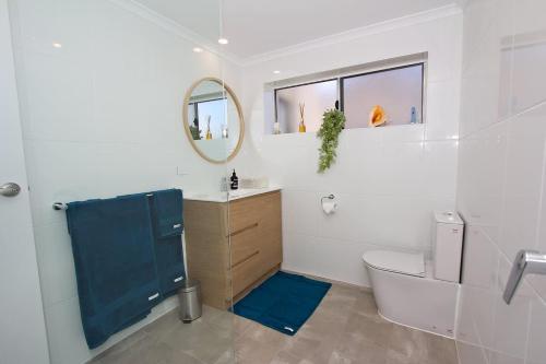 a bathroom with a toilet and a sink and a mirror at Beach Stayz Semaphore Three Bedroom Apartment in Port Adelaide