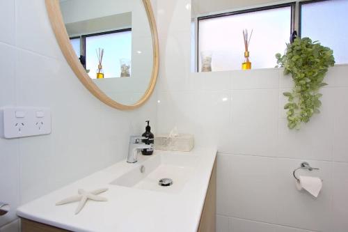 a white bathroom with a sink and a mirror at Beach Stayz Semaphore Three Bedroom Apartment in Port Adelaide