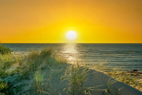 a sunset on a beach with the ocean at Beach Stayz Semaphore Three Bedroom Apartment in Port Adelaide