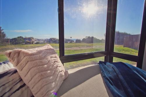 a pillow sitting on a couch in front of a window at Beach Stayz Semaphore Three Bedroom Apartment in Port Adelaide
