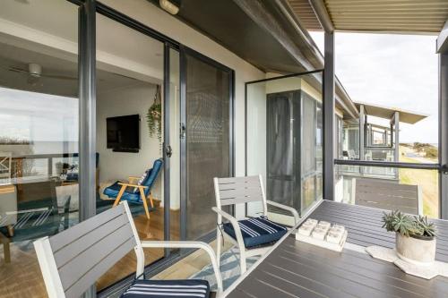 a house with a table and chairs on a balcony at Beach Stayz Semaphore Upstairs Two Bedroom Apartment in Port Adelaide