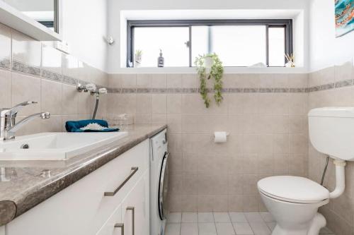 a white bathroom with a toilet and a sink at Beach Stayz Semaphore Upstairs Two Bedroom Apartment in Port Adelaide