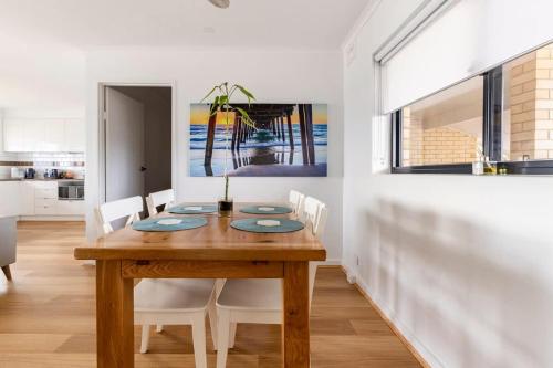 a dining room with a wooden table and white chairs at Beach Stayz Semaphore Upstairs Two Bedroom Apartment in Port Adelaide