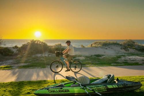 a man is riding a bike next to a boat at Beach Stayz Semaphore Upstairs Two Bedroom Apartment in Port Adelaide