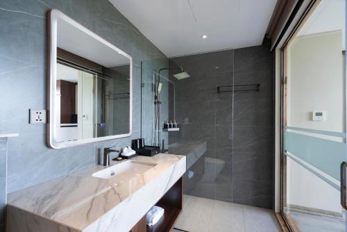 a bathroom with a sink and a mirror and a shower at Ruby Hotel Van Don in Tài Xá