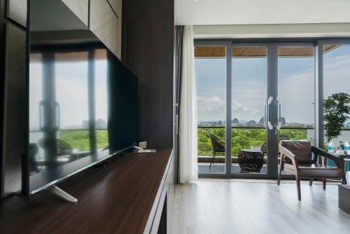 a living room with a large window and a table and chairs at Ruby Hotel Van Don in Tài Xá