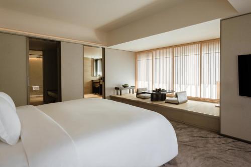 a bedroom with a large white bed and a large window at Dusit Thani Kyoto in Kyoto