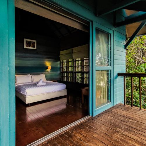 a bedroom with a bed on the porch of a house at Permai Rainforest Resort in Santubong