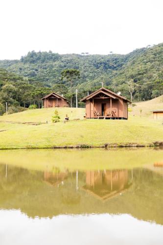 a couple of huts next to a body of water at Cabanas Recanto das Lagoas in Bom Retiro