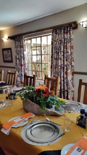 a dining room table with a plate and flowers on it at Riverside Lodge & Conference Center in Aliwal North