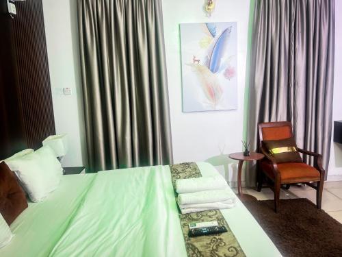 a hotel room with a bed and a chair at Kings Heights Apartments in Ikeja