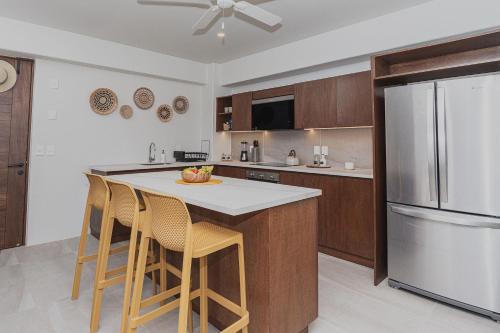 a kitchen with a island with chairs and a refrigerator at Brand New Condo near beach in Santa Cruz Huatulco