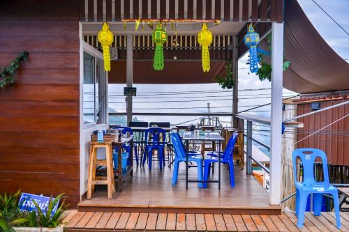 a patio with blue chairs and tables on a deck at Raisuayang in Mon Jam