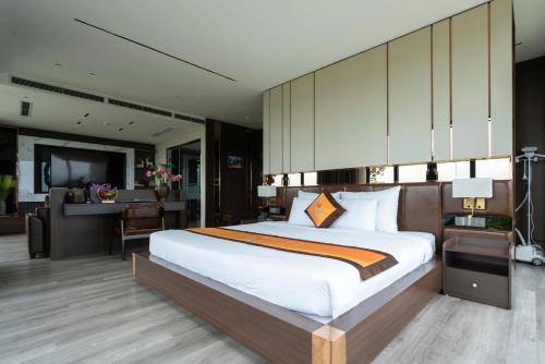 a bedroom with a large bed and a desk at Ruby Hotel Van Don in Tài Xá
