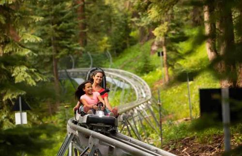 a woman and a child riding on a roller coaster at Fully Renovated 2 BR on River with Pool - Walk to Town! in Aspen