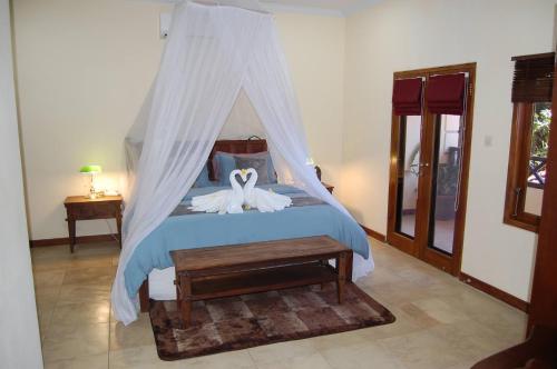 a bedroom with a bed with a mosquito net at Beachfront Villa Jepun Segara in Banjar