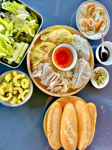 a table topped with plates of food with bread and salad at Điểm du lịch canh nông Avocado Farm in Lac Nghĩa