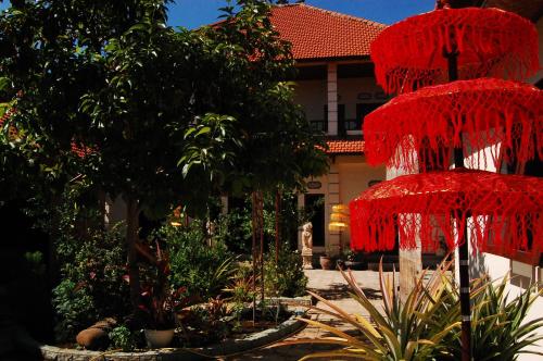 a garden with red umbrellas in front of a house at Beachfront Villa Jepun Segara in Banjar