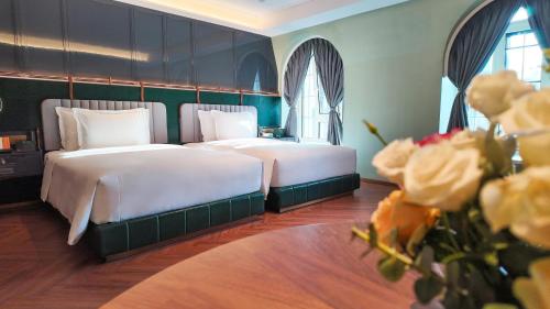 two beds in a hotel room with flowers at Hotel Indigo Harbin Central Avenue by IHG in Harbin