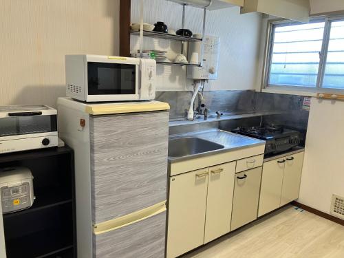 a kitchen with a microwave and a sink at テラハウス国立 Terahouse Kunitachi in Kunitachi