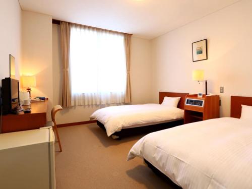 a hotel room with two beds and a window at KANEMITSU CAPITAL HOTEL in Takamatsu