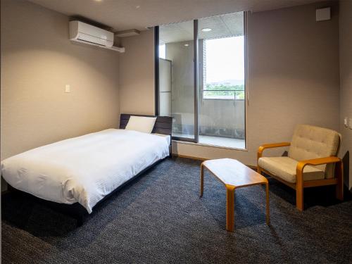a bedroom with a bed and a chair and a window at KANEMITSU CAPITAL HOTEL in Takamatsu