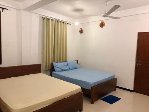a bedroom with two beds and a ceiling fan at Metro Stay in Kurunegala