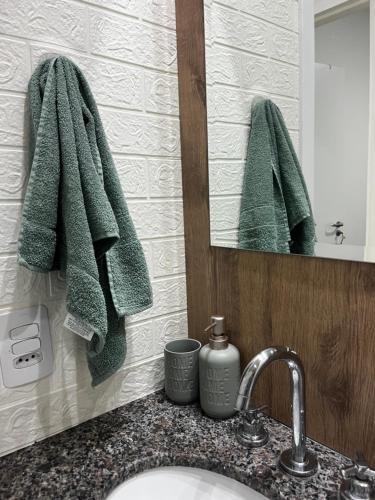 a bathroom with a sink and a mirror and green towels at Apartamento aconchegante NOVO LUXO Sao Bernardo do Campo in São Bernardo do Campo