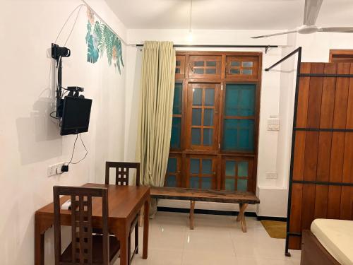 a room with a wooden door and a table and a television at Metro Stay in Kurunegala