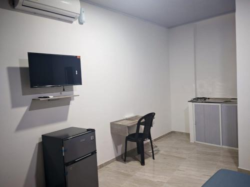 a room with a chair and a tv on a wall at hotel Air b&b altos del peñon in Girardot