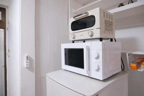 a microwave sitting on top of a white refrigerator at Yado75 in Nago