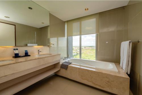 a bathroom with a tub and a sink and a window at Grand Tan Banjarmasin Hotel & Convention Center in Banjarmasin