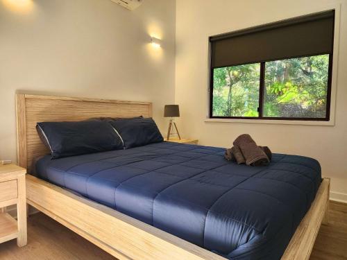 a bedroom with a large blue bed with a window at 718 Cooloola Villa at Kingfisher Bay, K'gari Fraser Island in K'gari Island (Fraser Island)