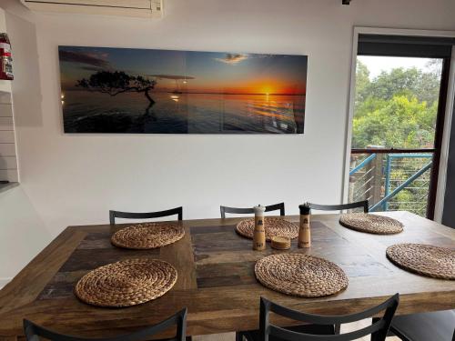 a wooden table with chairs and a large painting on the wall at 718 Cooloola Villa at Kingfisher Bay, K'gari Fraser Island in K'gari Island (Fraser Island)