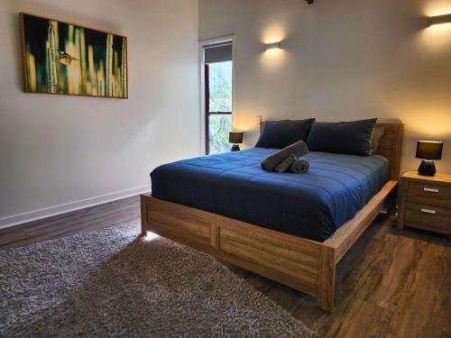 a bedroom with a bed with blue sheets and a window at 719 Cooloola Villa at Kingfisher Bay K'gari Fraser Island in K'gari Island (Fraser Island)