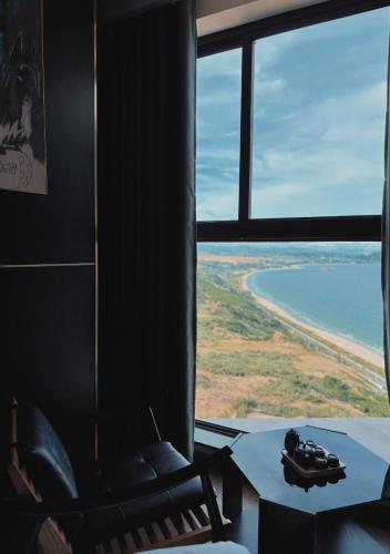 a room with a chair and a view of the ocean at Condotel SeaSide - Apec Mandala Cham Bay Mui Ne in Mui Ne