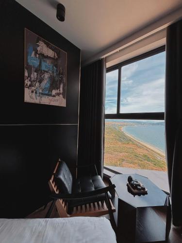 a bedroom with a chair and a large window at Condotel SeaSide - Apec Mandala Cham Bay Mui Ne in Mui Ne