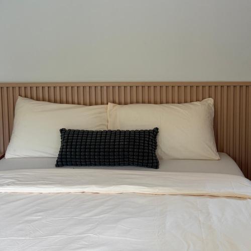 a bed with white pillows and a black pillow at กางเขา แคมป์ปิ้ง in Ban Bung Mai