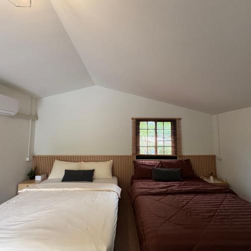 two beds in a small room with a window at กางเขา แคมป์ปิ้ง in Ban Bung Mai