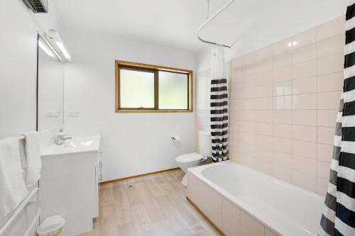 a bathroom with a tub and a toilet and a sink at Sullivans Retreat - Paihia Holiday Home in Paihia