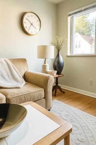 a living room with a couch and a clock on the wall at Urban Oasis in the Heart of STL in Saint Louis