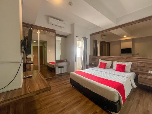 a bedroom with a large bed with red pillows at RedDoorz Apartment near Exit Toll Colomadu in Solo