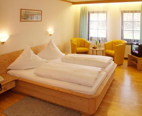 a bedroom with a large bed and two yellow chairs at Landgasthof Goldene Rose in Grub am Forst
